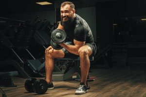 Homme sportif réalisant un biceps curl avec une haltère.